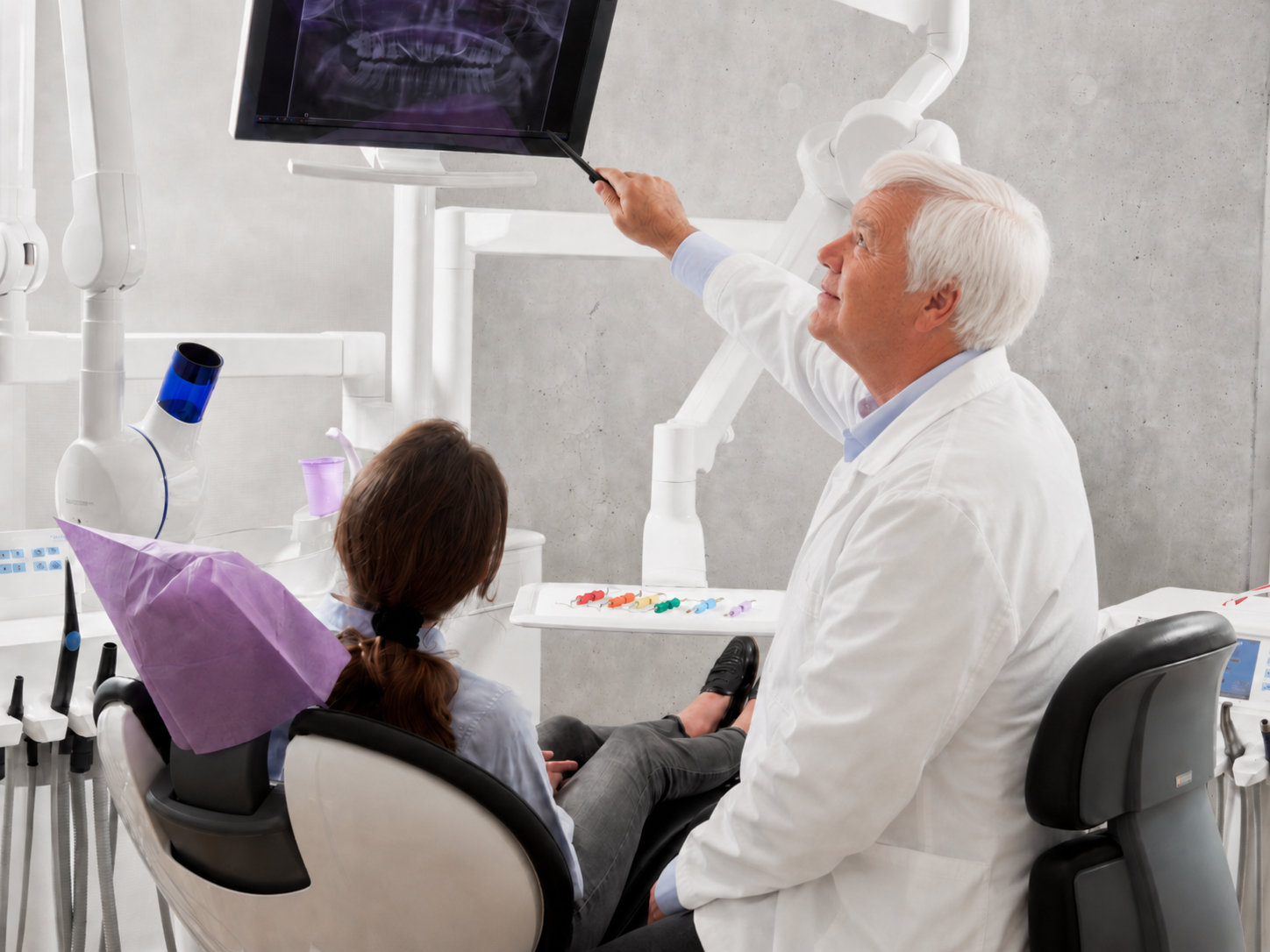 Dr. Andrew Lovrics reviewing a panoramic dental X-ray with a patient in the treatment chair. Photo by Caroline LM on Unsplash.